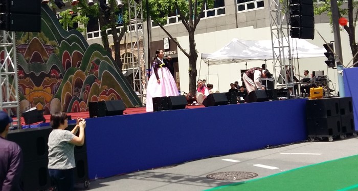 A Korean woman singing, with what resembled a conga line, though was probably supposed to be a dragon.